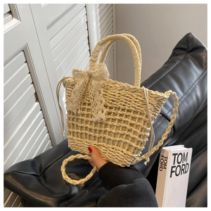 Close-up of handmade straw beach bag with delicate lace bow and round wooden handles