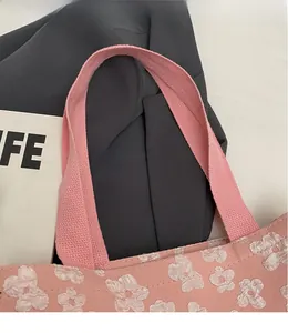 Detailed close-up of pink floral tote bag featuring 3D flowers and woven shoulder straps