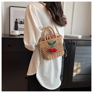 Detail of hand-woven straw beach bag with 3D cherry accents and drawstring liner