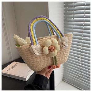 Detail of hand-woven straw bag with rainbow handles and plush floral accent