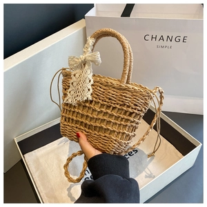 Detail of hand-woven straw tote with white lace bow and drawstring inner lining