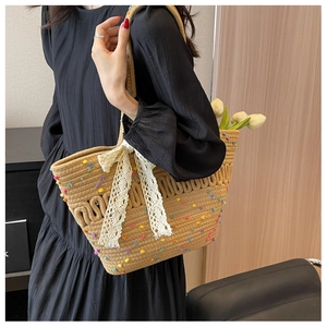 Détail du sac cabas en paille tissée avec pois colorés et un nœud en dentelle blanche
