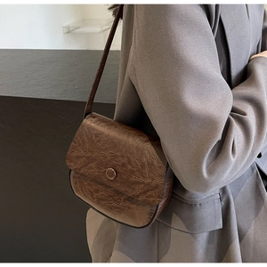 Detail of dark brown vintage faux leather shoulder bag with circular buckle decor
