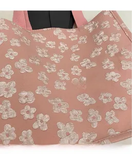 Close-up of light pink canvas tote bag featuring 3D floral texture and woven handles