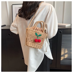 Detail of hand-woven straw bag featuring 3D red cherry decor and drawstring lining