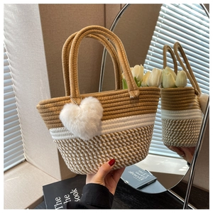 Detail der handgewebten Strohtasche mit Streifenmuster und weißem Herz-Anhänger