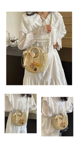 Detail of handmade straw bag with floral accents and a lace bow charm on crossbody strap