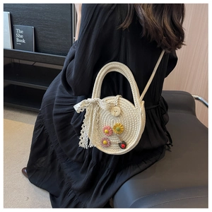 Detailaufnahme der runden gewebten Tasche mit Blumenmustern und einer Schleife aus Spitze
