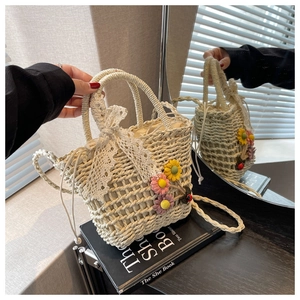 Detail of hand-woven straw bag featuring 3D crochet flowers and delicate lace bow