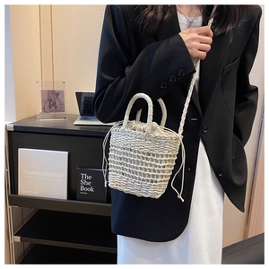 Detailed view of hand-woven cream bucket bag with drawstring closure and shoulder strap
