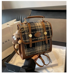 Details eines Vintage-Rucksacks mit Karomuster, Metallschnalle und Plüsch-Affen-Anhänger