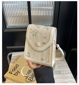 Détail du sac bandoulière tissé crème avec broderie florale verte et garniture en cuir PU