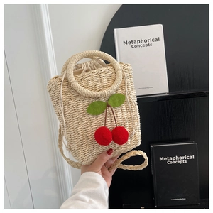 Detail of hand-woven straw bag with red cherry accents and a drawstring closure