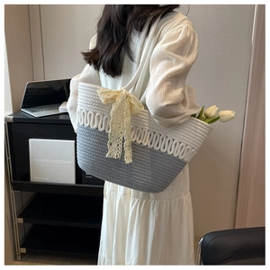 Détail du sac de plage tissé à la main avec motif contrasté gris-blanc et nœud en dentelle