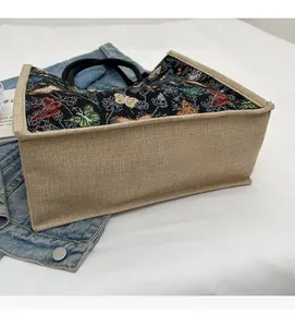 Détail de broderie papillon sur un sac fourre-tout avec empiècement en jute beige