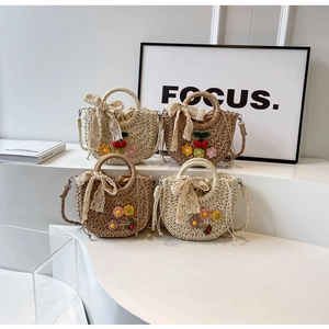 Close-up of handmade straw bags with lace bows and 3D flowers on display stand