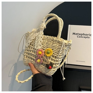 Close-up of handwoven straw tote with crochet flowers and a decorative lace bow handle