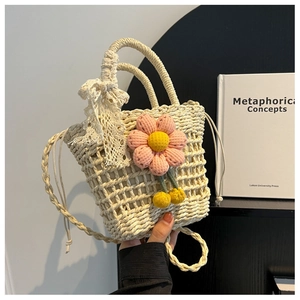 Close-up of handmade beige straw woven bag with pink knitted flowers and lace bow detail