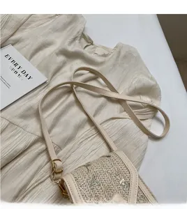 Détail d'un sac bandoulière en paille avec broderie florale et fine lanière en cuir