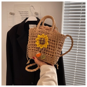 Detail of straw woven crossbody bag with sunflower decor and drawstring lining