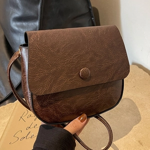 Retro dark brown saddle bag with crackle texture and flap closure in a minimalist style