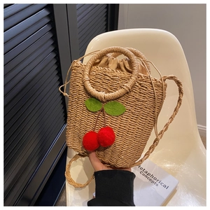 Close-up of straw woven handbag with cherry decorations and drawstring lining