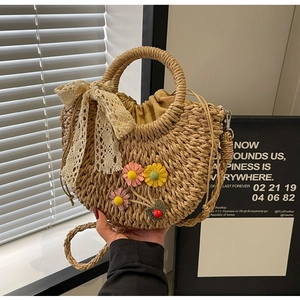 Detail of handmade straw saddle bag with 3D floral accents and beige lace ribbon