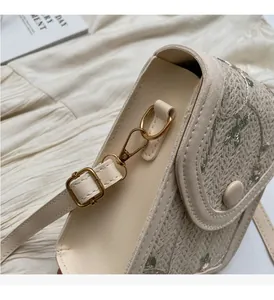 Gros plan détaillé sur la paille beige brodée et les ferrures dorées du sac à bandoulière