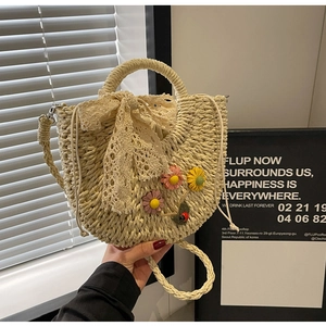 Detail of hand-woven straw bag with lace bow, floral accents, and drawstring liner