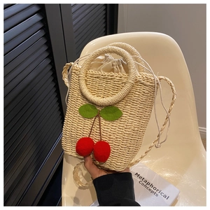 Detail of woven straw bag with cherry embellishments, ring handle and drawstring lining