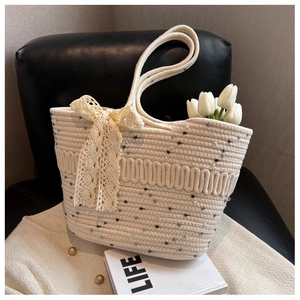 Gros plan sur un sac de plage tissé orné d'un délicat nœud en dentelle beige