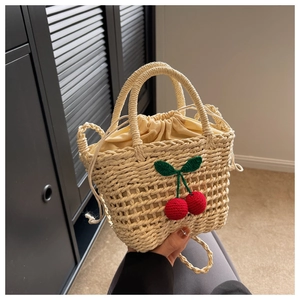 Detail of hand-woven beige beach bag with red crochet cherry charms and drawstring liner