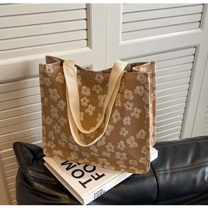Detailed macro view of the beige floral textured canvas tote bag with wide strap handles