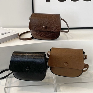 Three semi-circular crossbody bags in dark coffee, black, and light brown faux leather