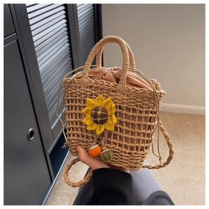 Detailed close-up of handmade straw bucket bag with sunflower decor and drawstring inner