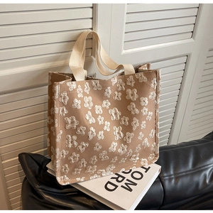 Macro detail of textured 3D floral jacquard pattern on a large beige canvas tote bag