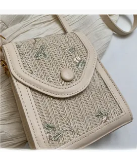 Gros plan sur le sac bandoulière en paille beige avec broderie florale et détails cuir