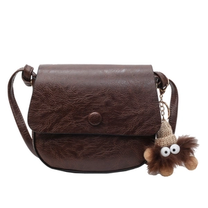 Retro dark brown saddle crossbody bag with a plush bear charm and adjustable strap