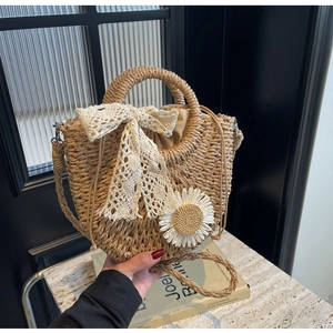 Detail of handmade straw bag with lace bow, daisy accent and drawstring closure
