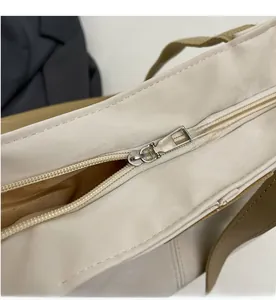 Detail view of smooth silver metal zipper and durable cream nylon fabric on tote bag