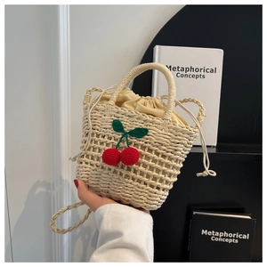 Close-up of handmade woven straw bag with knit cherry detail and drawstring inner liner