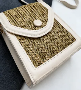 Detail of hand-woven straw crossbody bag with PU leather trim and round snap closure