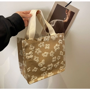 Close-up of canvas tote bag with 3D floral tufting details and golden snap button