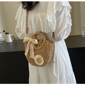 Detail of hand-woven straw bag with white daisies, lace bow and drawstring closure