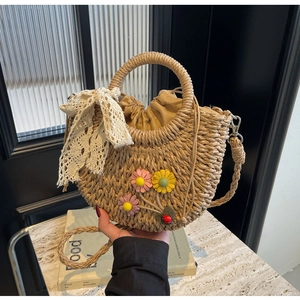 Detailed view of handmade straw bag with colorful fabric daisies and lace bow detail
