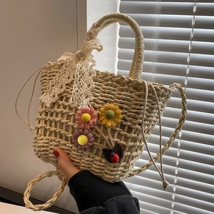 Handwoven straw beach bag with floral crochet accents and white lace ribbon bow