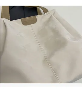Close-up of matte textured tote bag showing fine stitching and embossed fashion logo tag