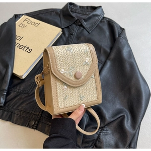 Détail d'un sac à bandoulière en paille tissée avec broderie florale et bords en cuir