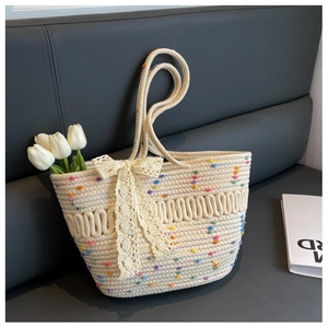 Vue détaillée du sac cabas de plage tissé avec pompons colorés, nœud en dentelle et anses