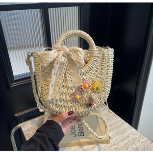 Close-up of handmade straw bucket bag featuring a white lace bow and daisy floral accents